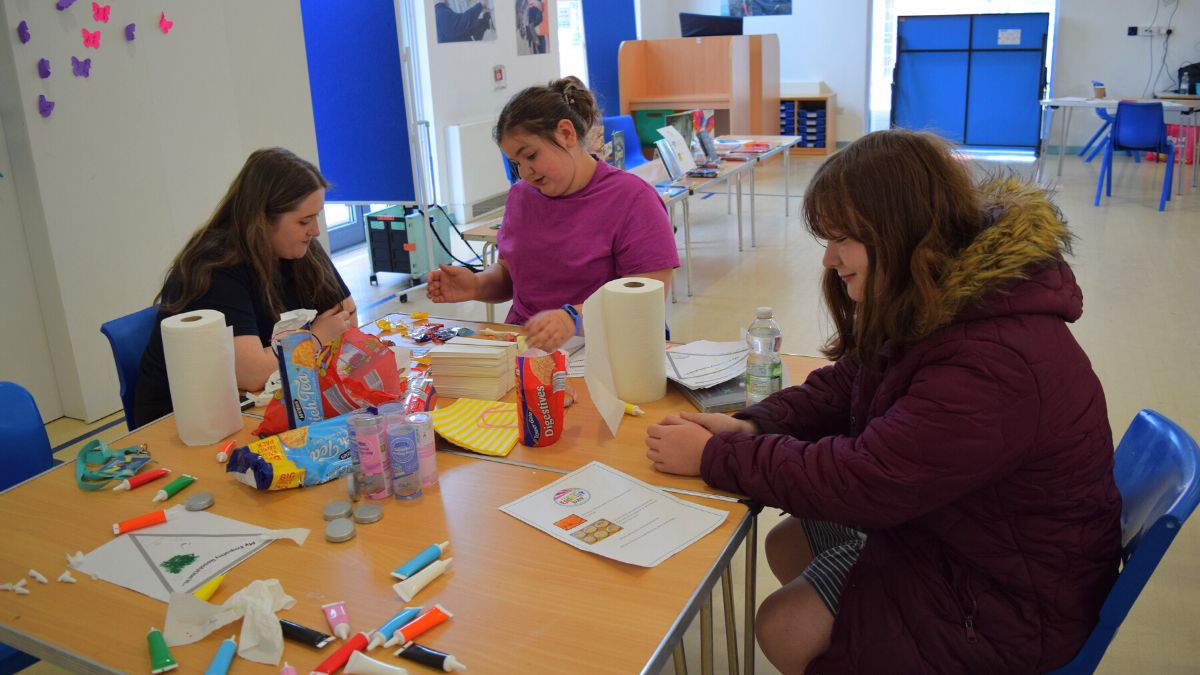 A group of students and staff member at the biscuit decorating table.