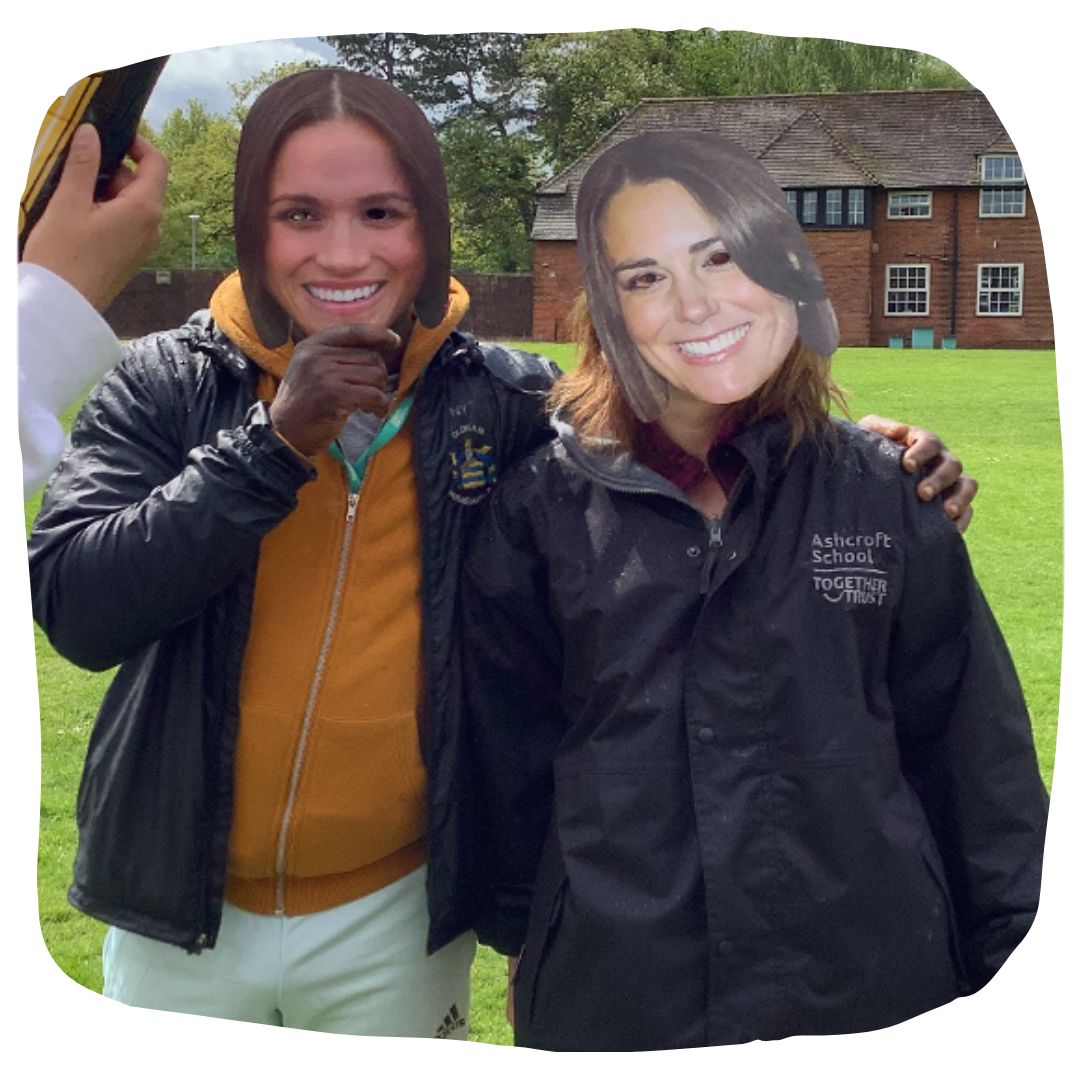 Staff members posing with face masks of Meghan Markle and Kate Middleton