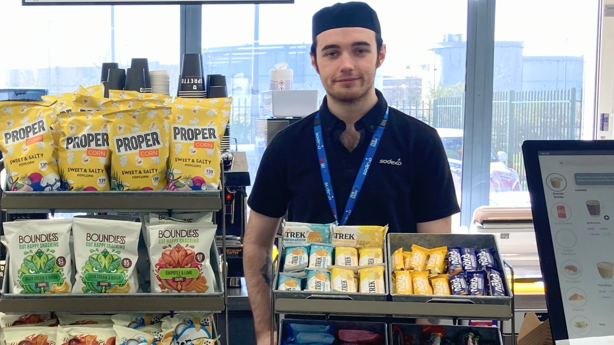 Bayleigh is stood behind the counter in the staff cafe ready to serve his customers