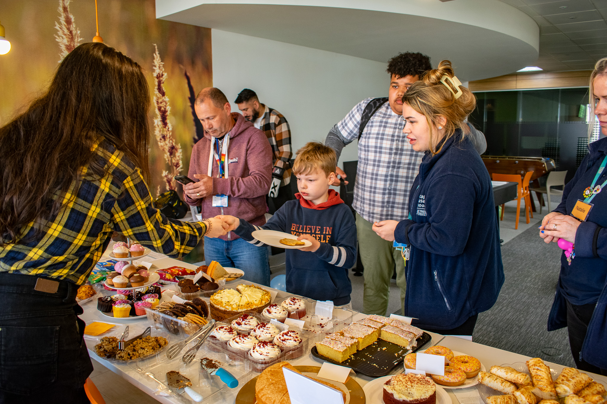 Alfie, Mason and a staff member look over a big selection of cakes.