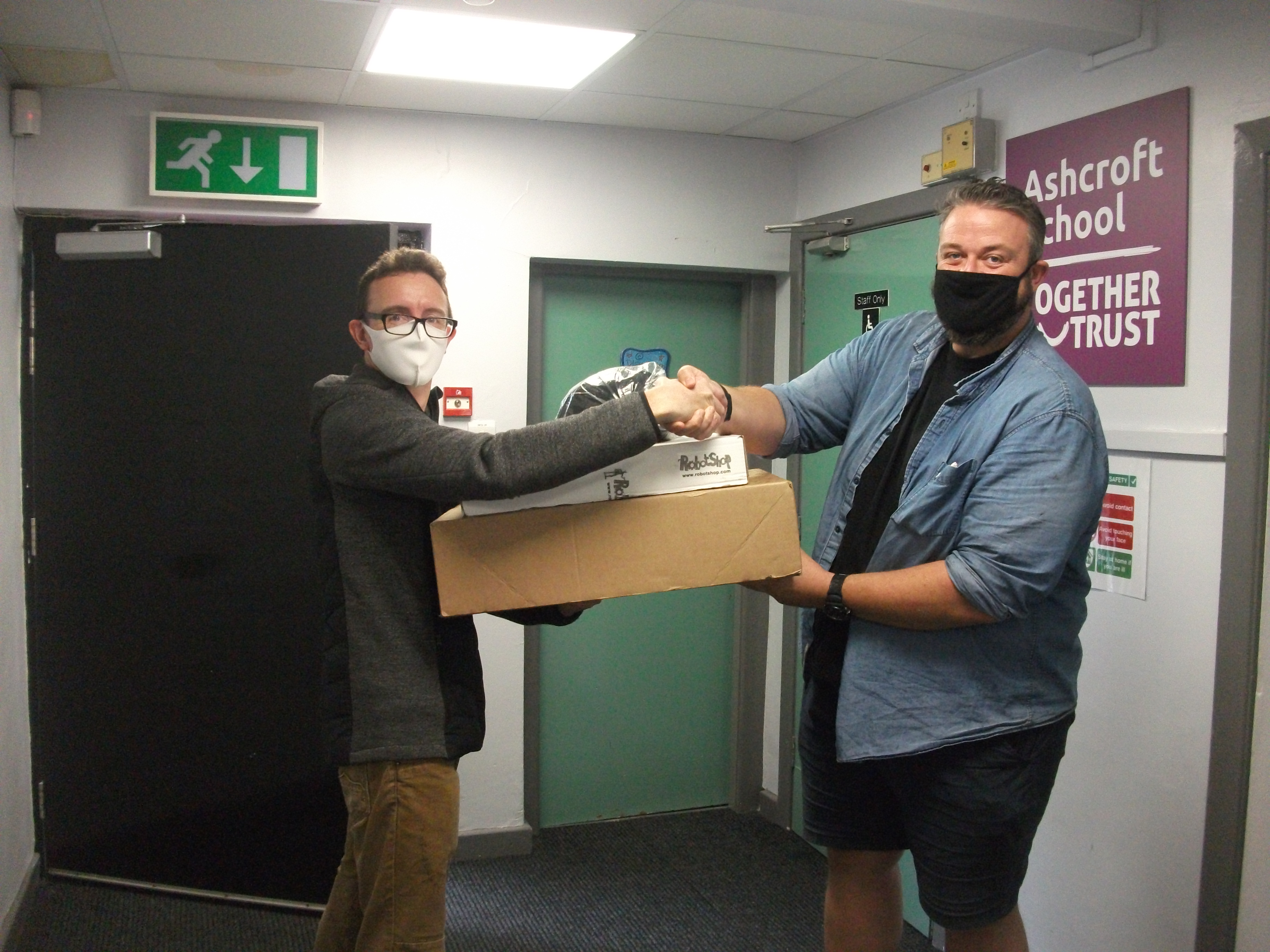 two men shaking hands as they hand over a box