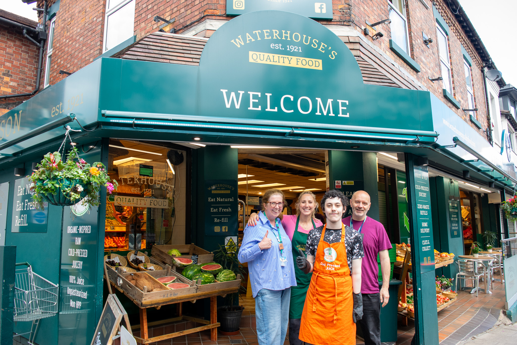 A boy is posing in front of the shop alongside Jen, the manager, Marie, the careers teacher and one of his Educational Assistants. 