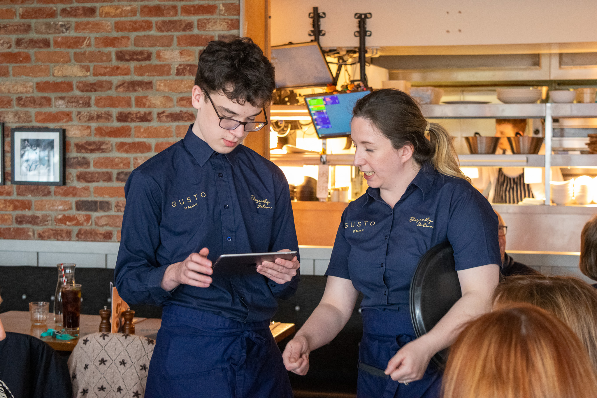 A young person and a member of staff, both wearing smart uniforms, completing an order on a tablet. 