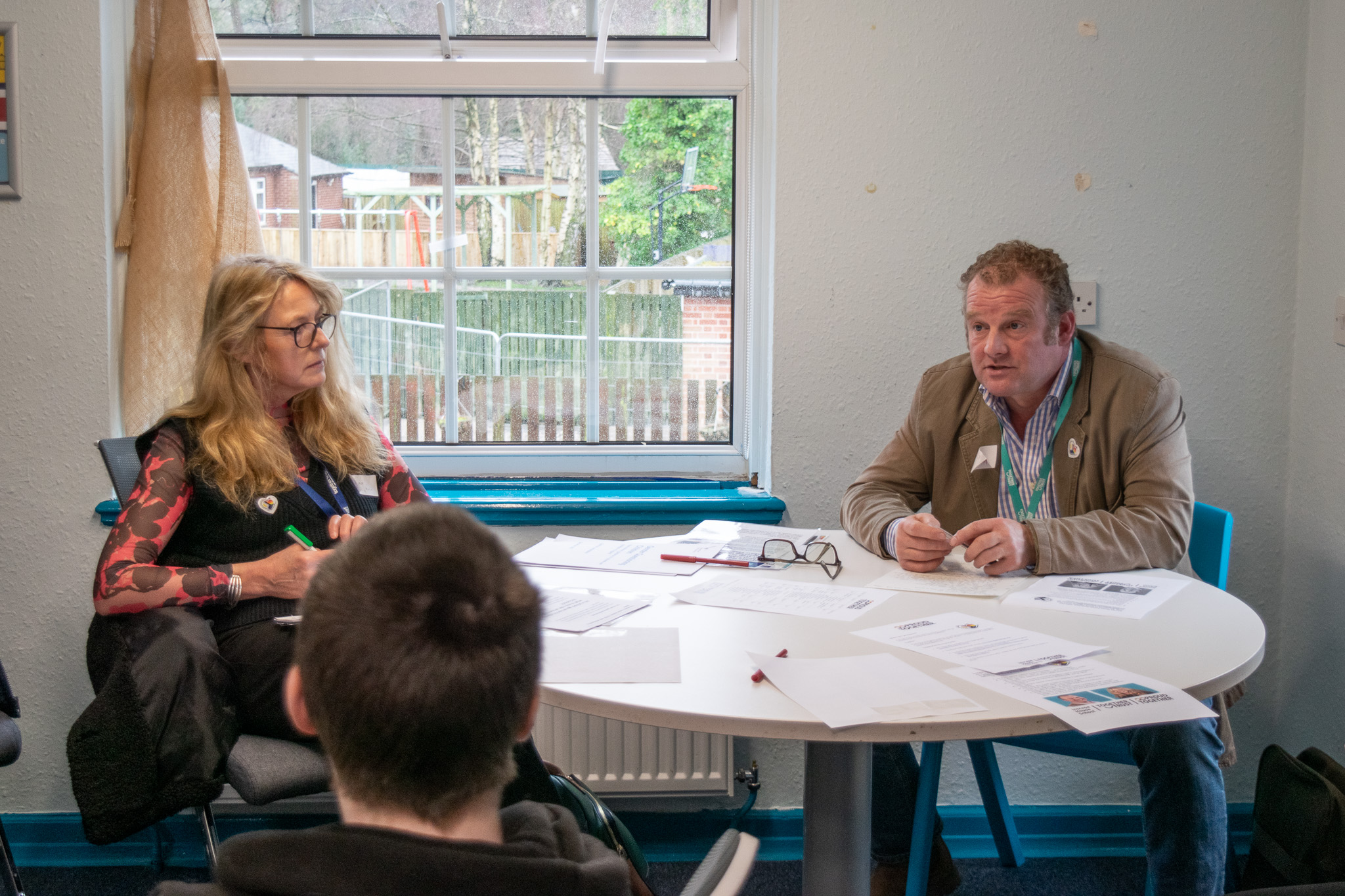 Two governors, Giles and Jane, sitting around a round table having a discussion with students. 