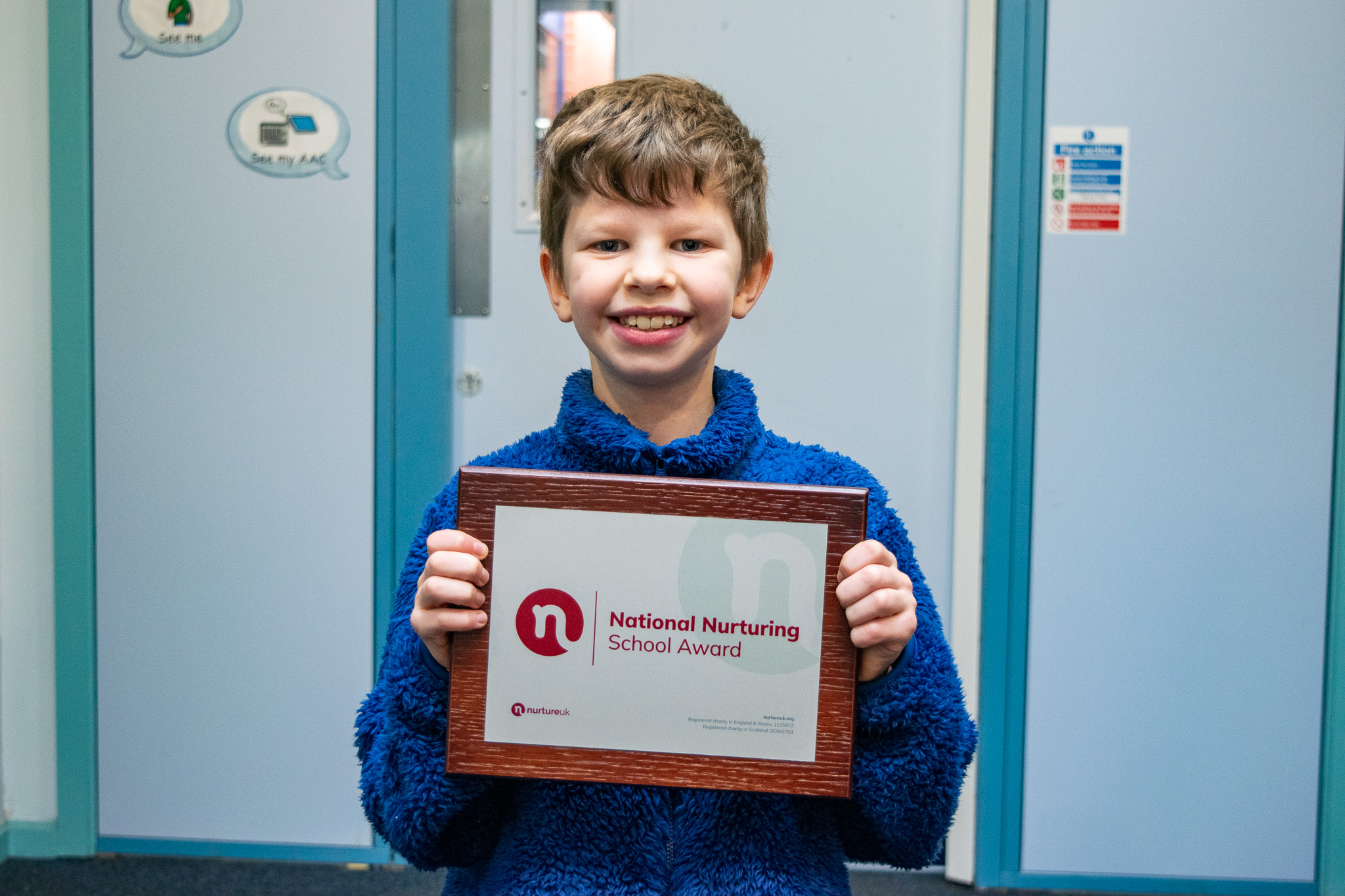 A pupil holding the certificate and smiling for a photo