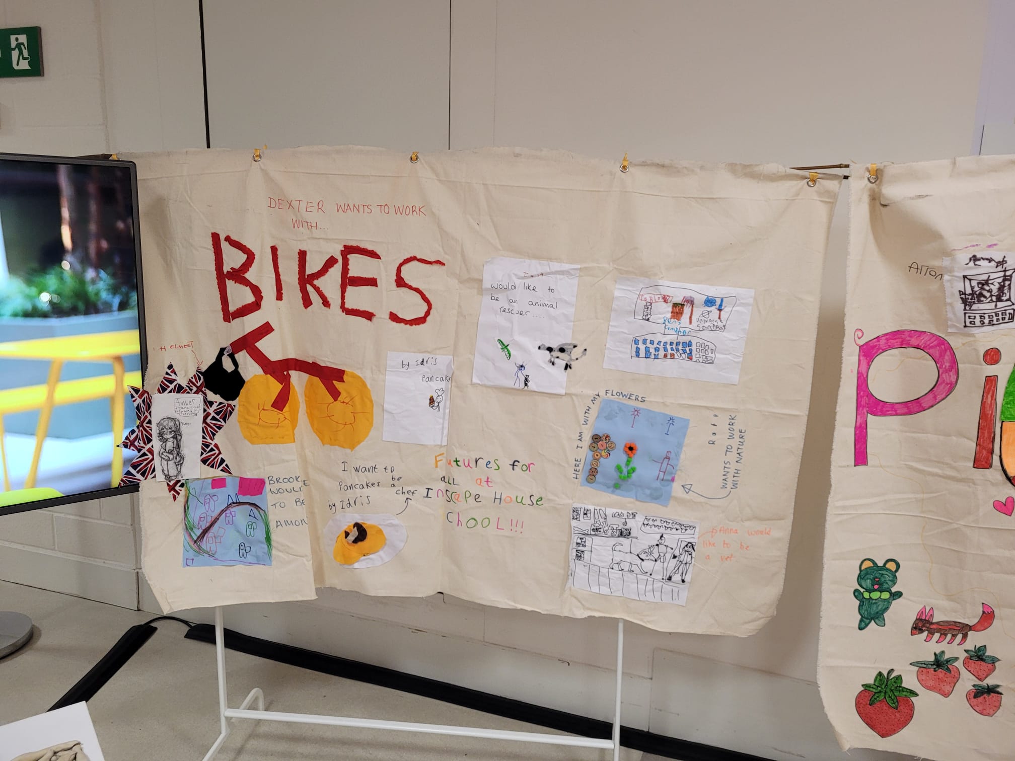 A large textile panel on which there are multiple pieces of artwork from students at inscape house school.