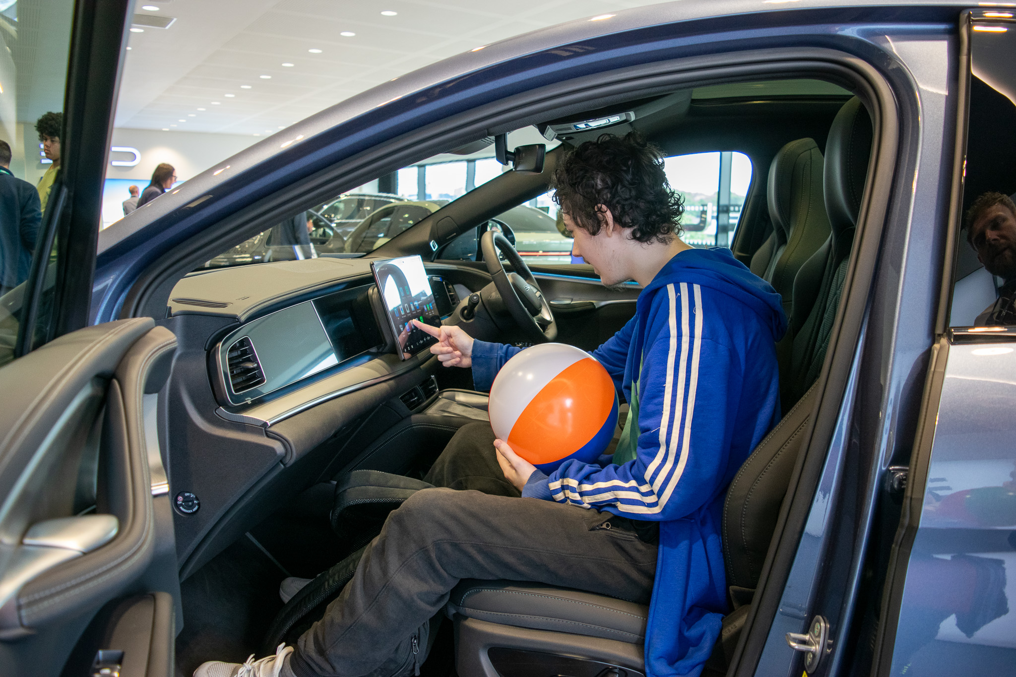 teen boy sitting in a car touching the car's digital control system 
