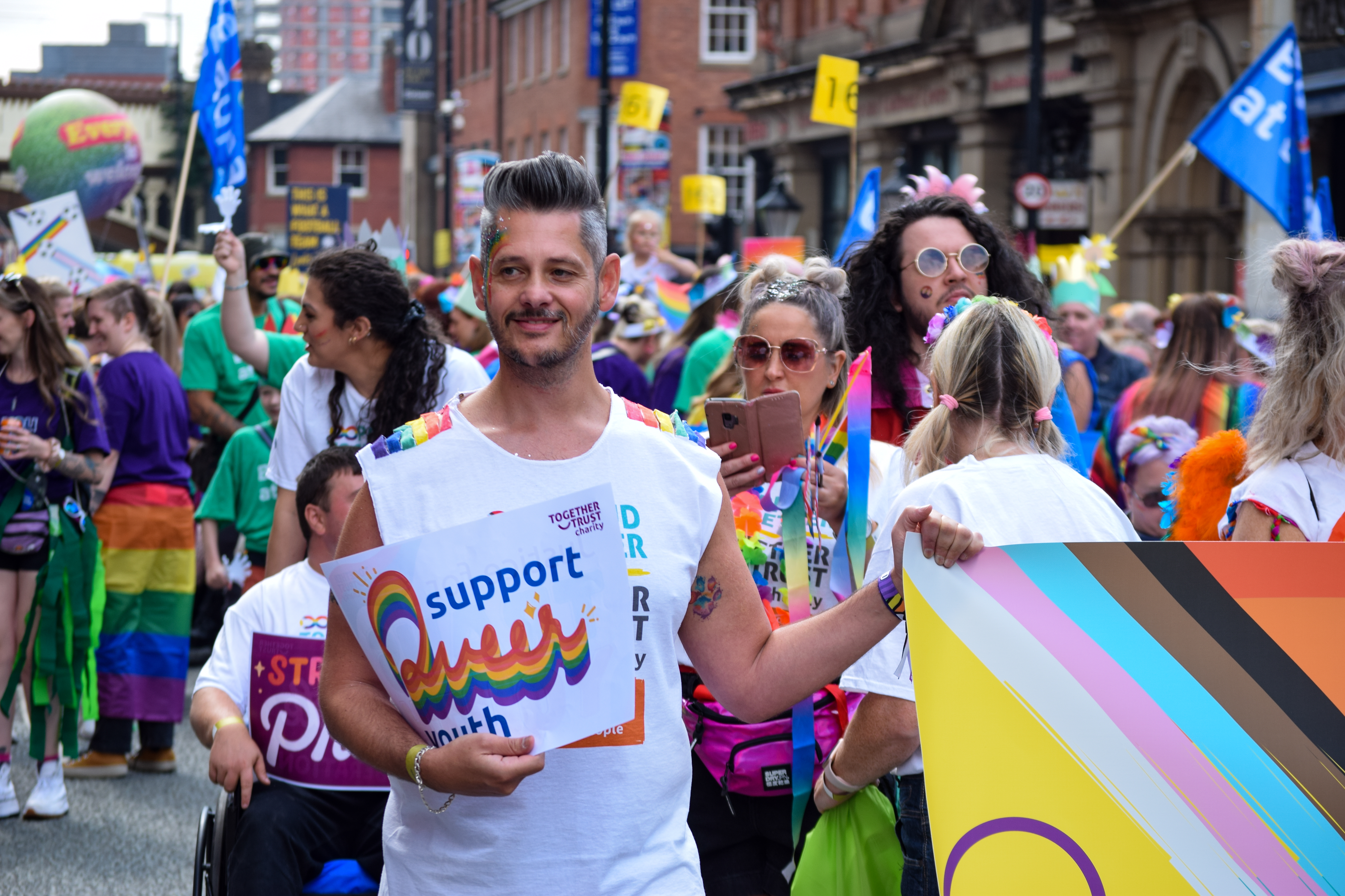 Man at pride parade holding sign that reads "protect queer youth" 