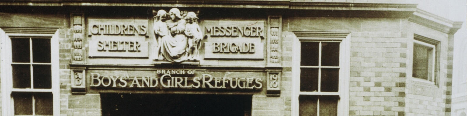 Old black and white photograph of building. The sign on it reads "Children's Shealter and Messenger Brigade. Branch of Boys and Girls Refuges"