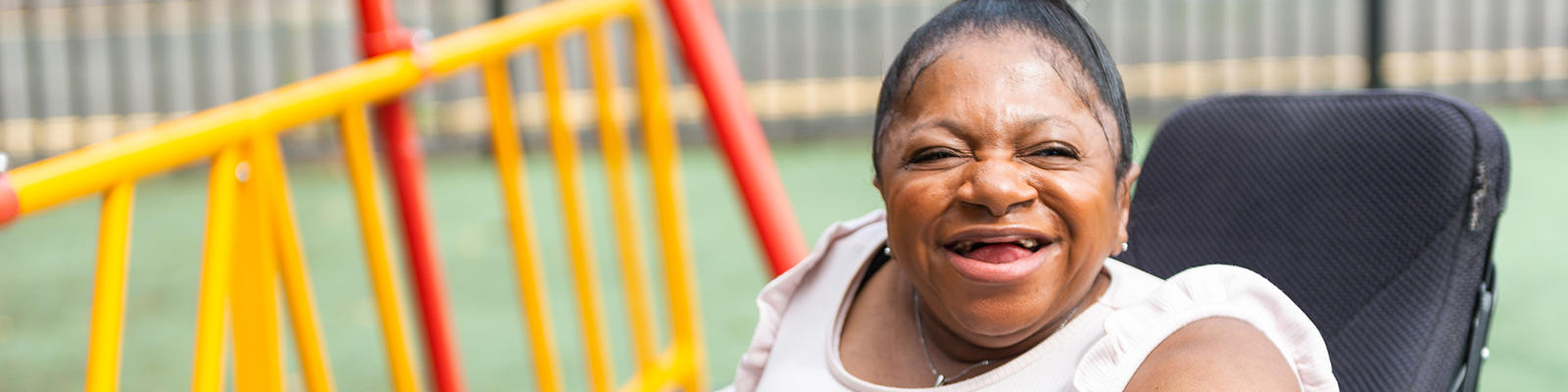Black disabled woman in a wheelchair smiling wide at the camera