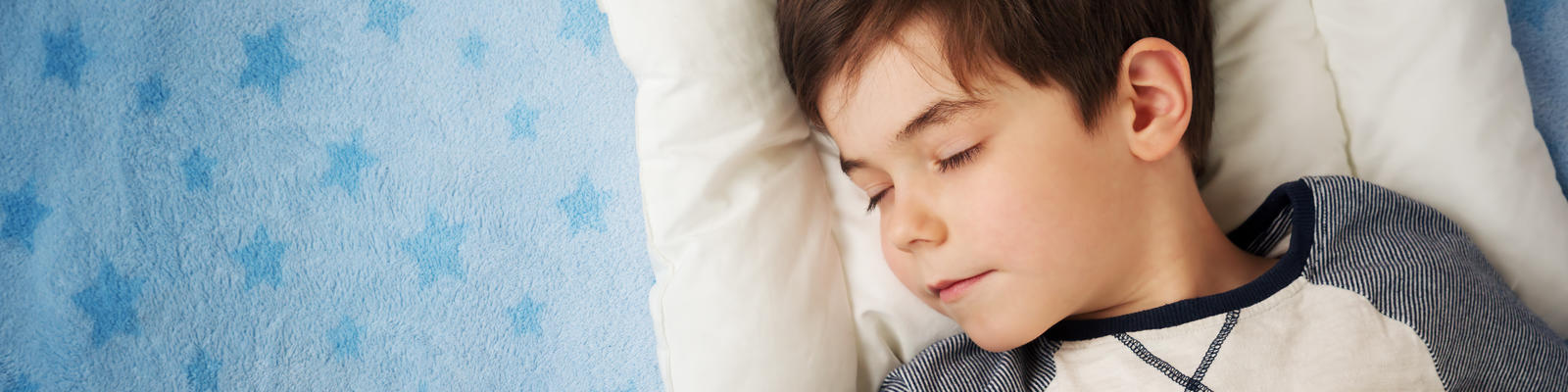 Young boy sleeping with a teddy in his arms 