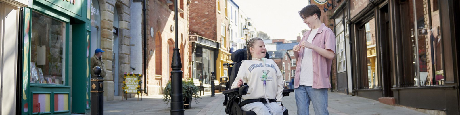 Girl in wheelchair and her care worker walking through the Stockport underbank 