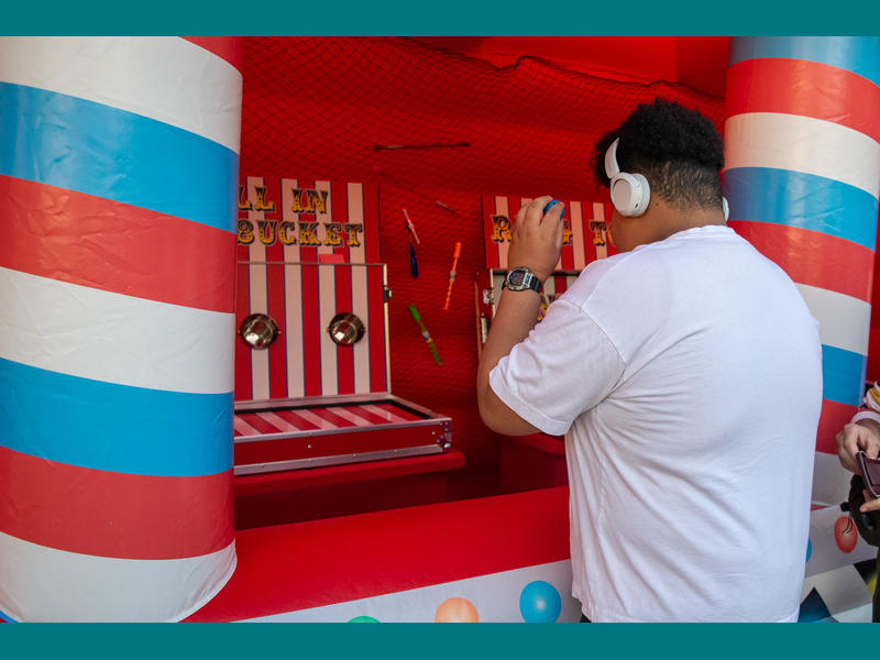 Young man wearing noise-cancelling headphones playing a carnival game.