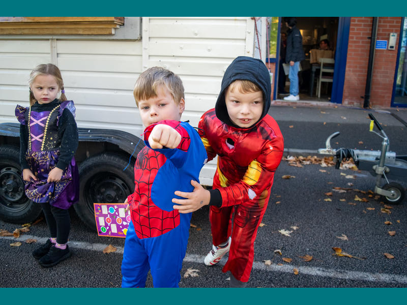 Three children in fancy dress, with one boy dressed as Spider Man holding his arm out to the camera to 'shoot webs'.