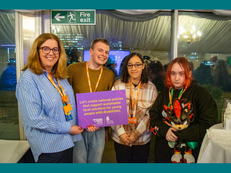 Staff member Marie with students Alex, Saffron and Ebony posing with a placard that says: ‘Let’s create national policies that support sustainable local solutions for young people with disabilities.’