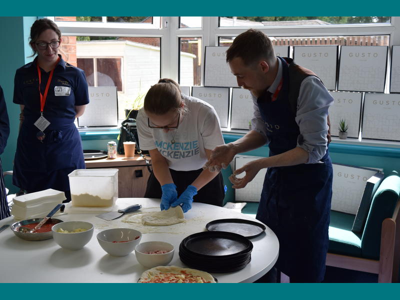 Mikey teaching Faye how to stretch out the pizza dough.