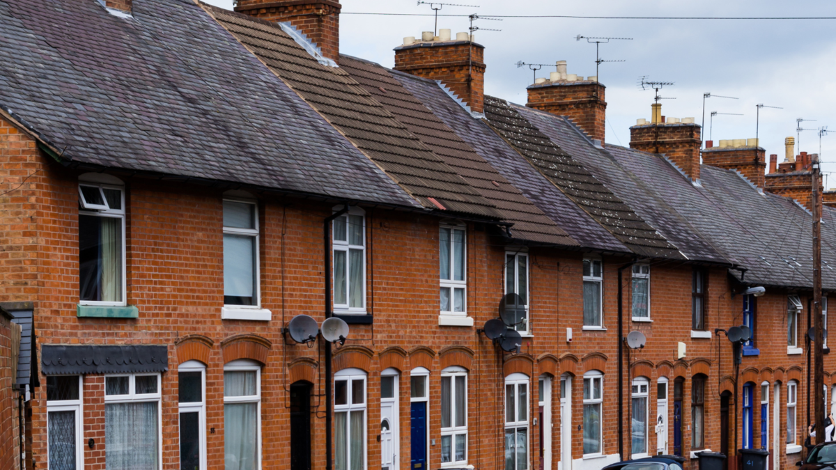 Row of terraced houses in England in front of a grey sky.