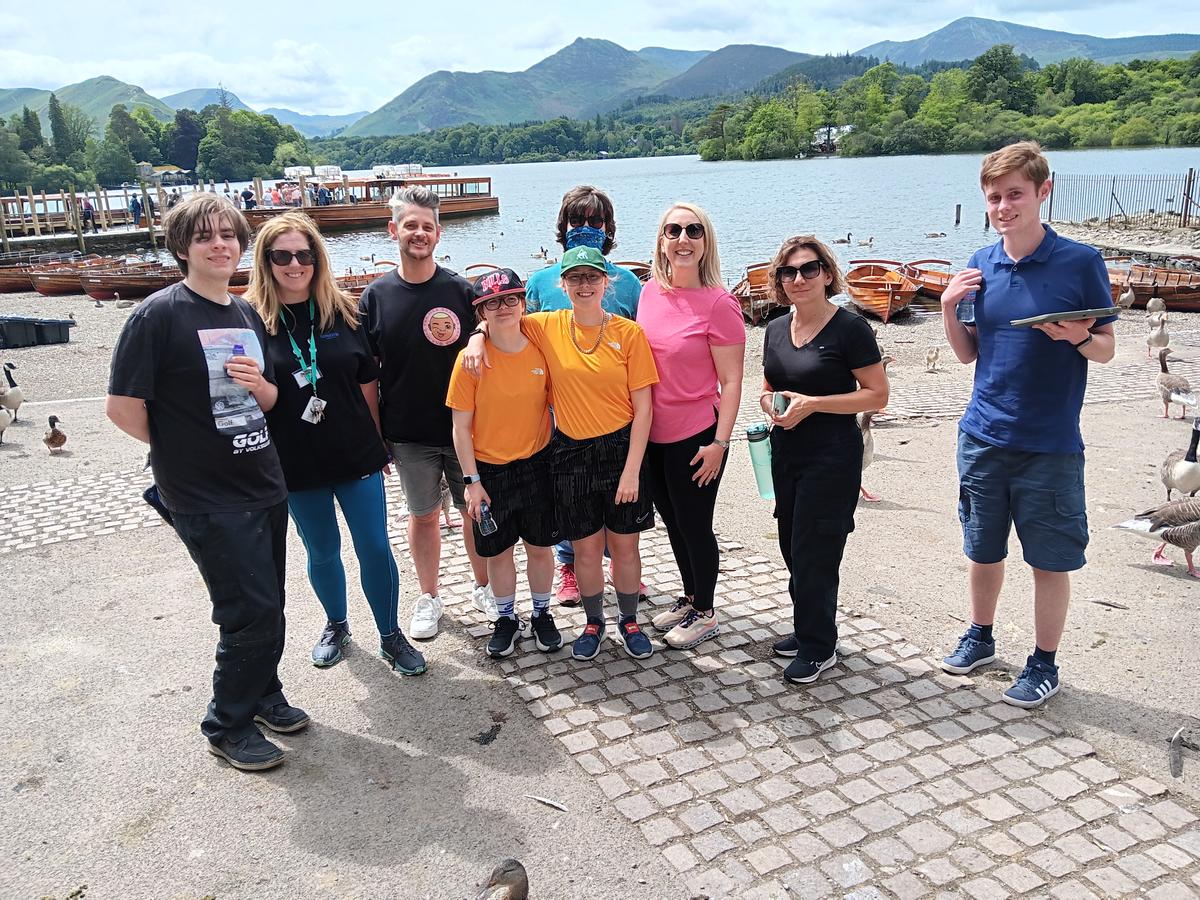 A group of students and staff members posing in front of a lake