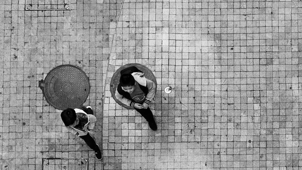 Birdseye photo of two young people walking down a street.