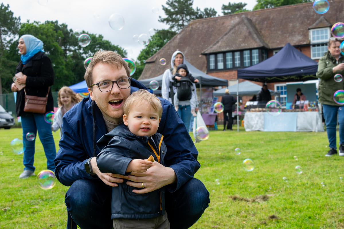 a man and a young boy smiling at bubbles in the air