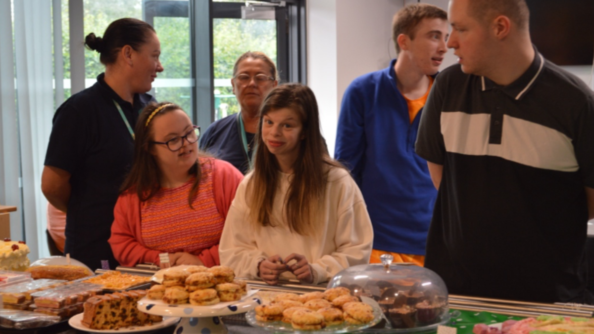 students looking at cakes on a table and smiling to the camera 