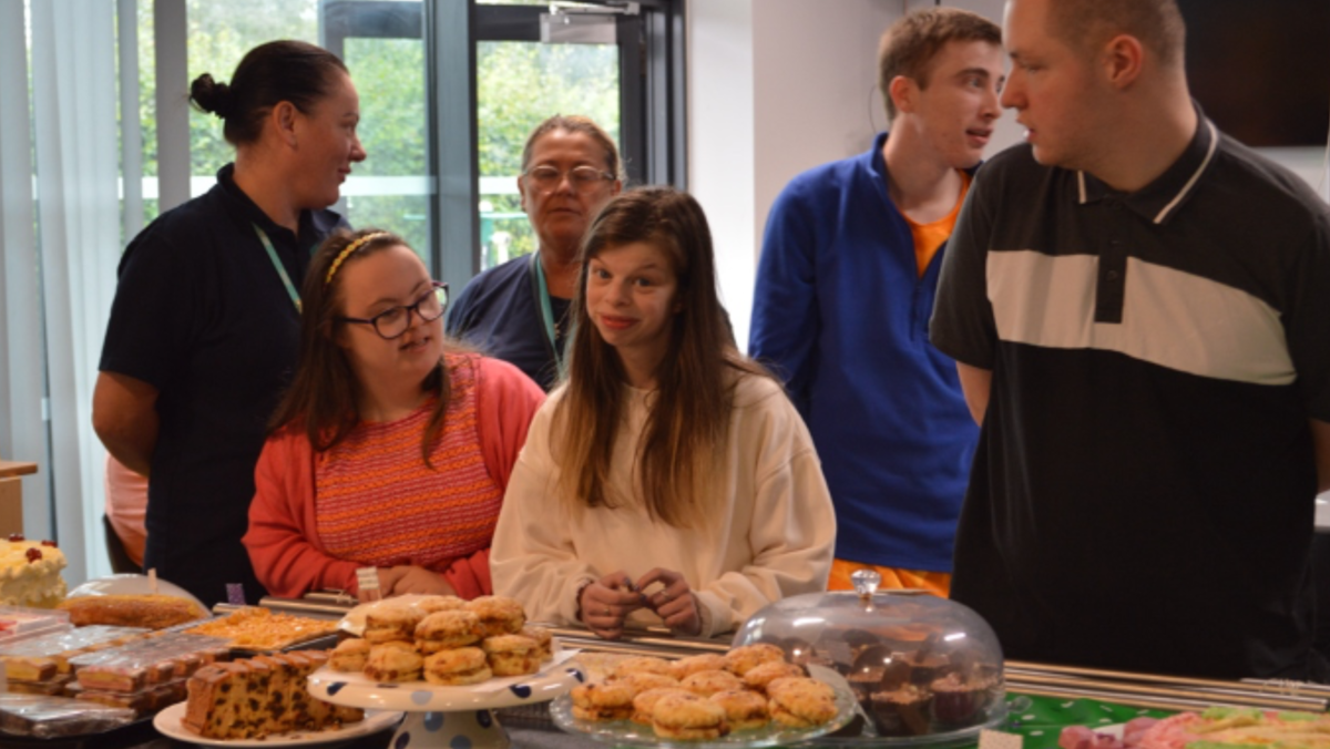 students looking at cakes on a table and smiling to the camera