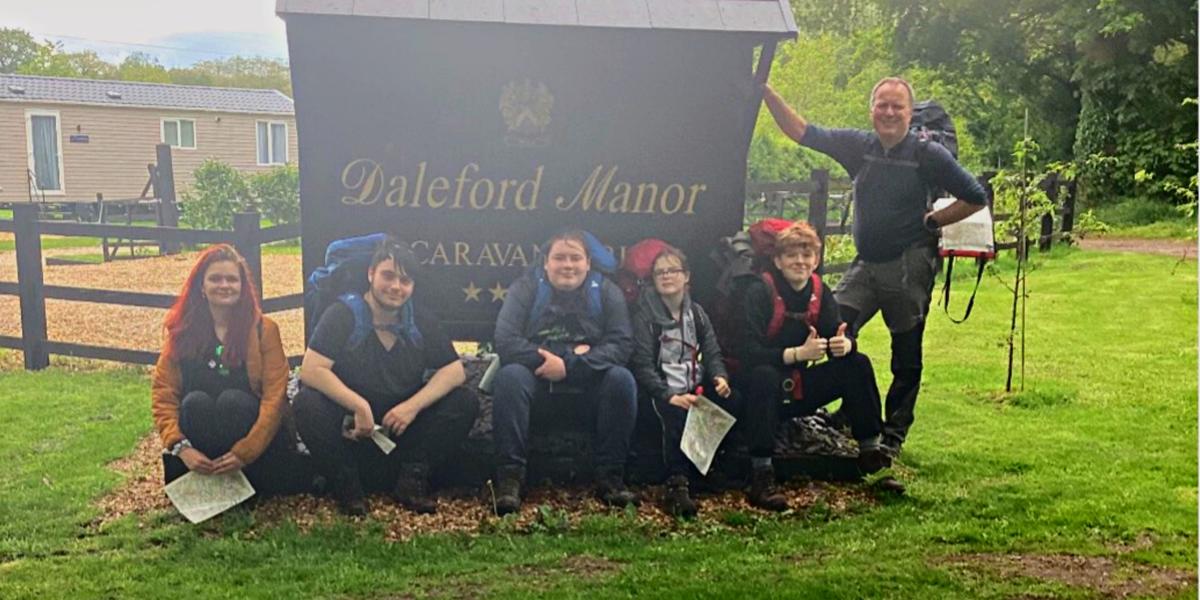 A group of students with staff members in front of the sign of Daleford Manor in Cheshire Country Park.