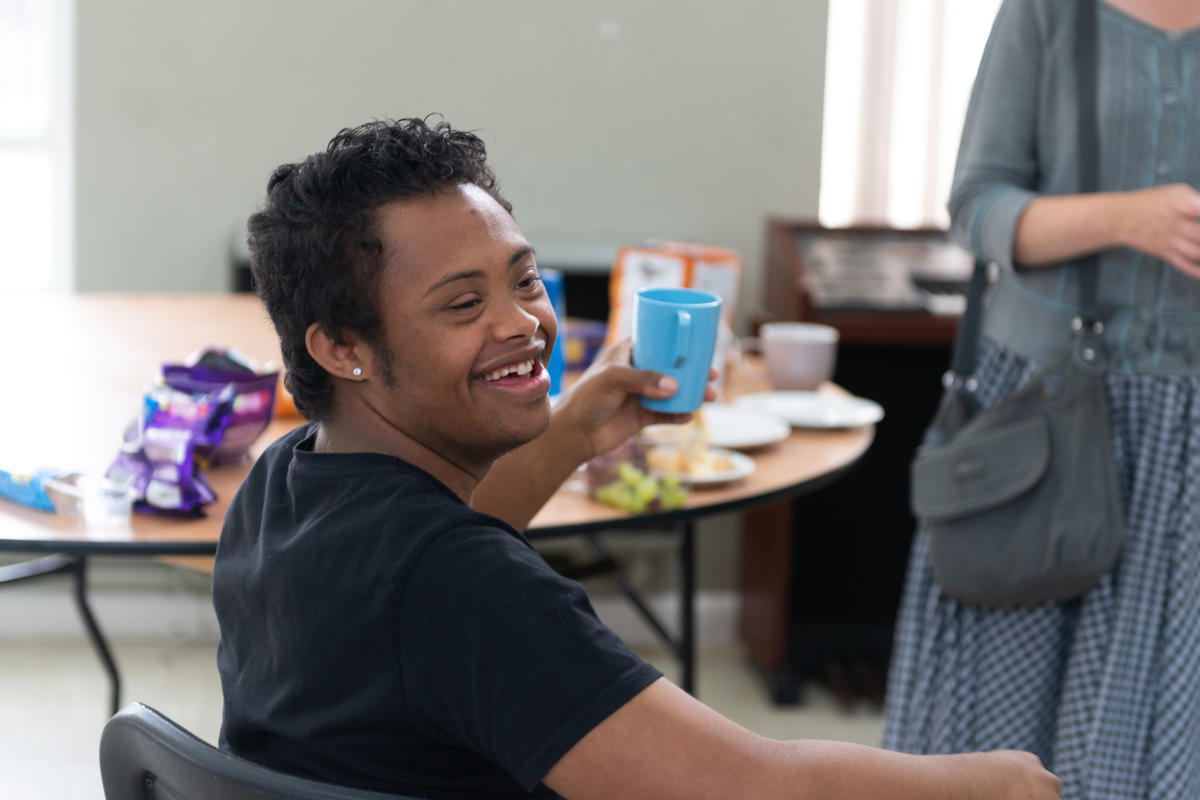 a young person holding a cup and smiling