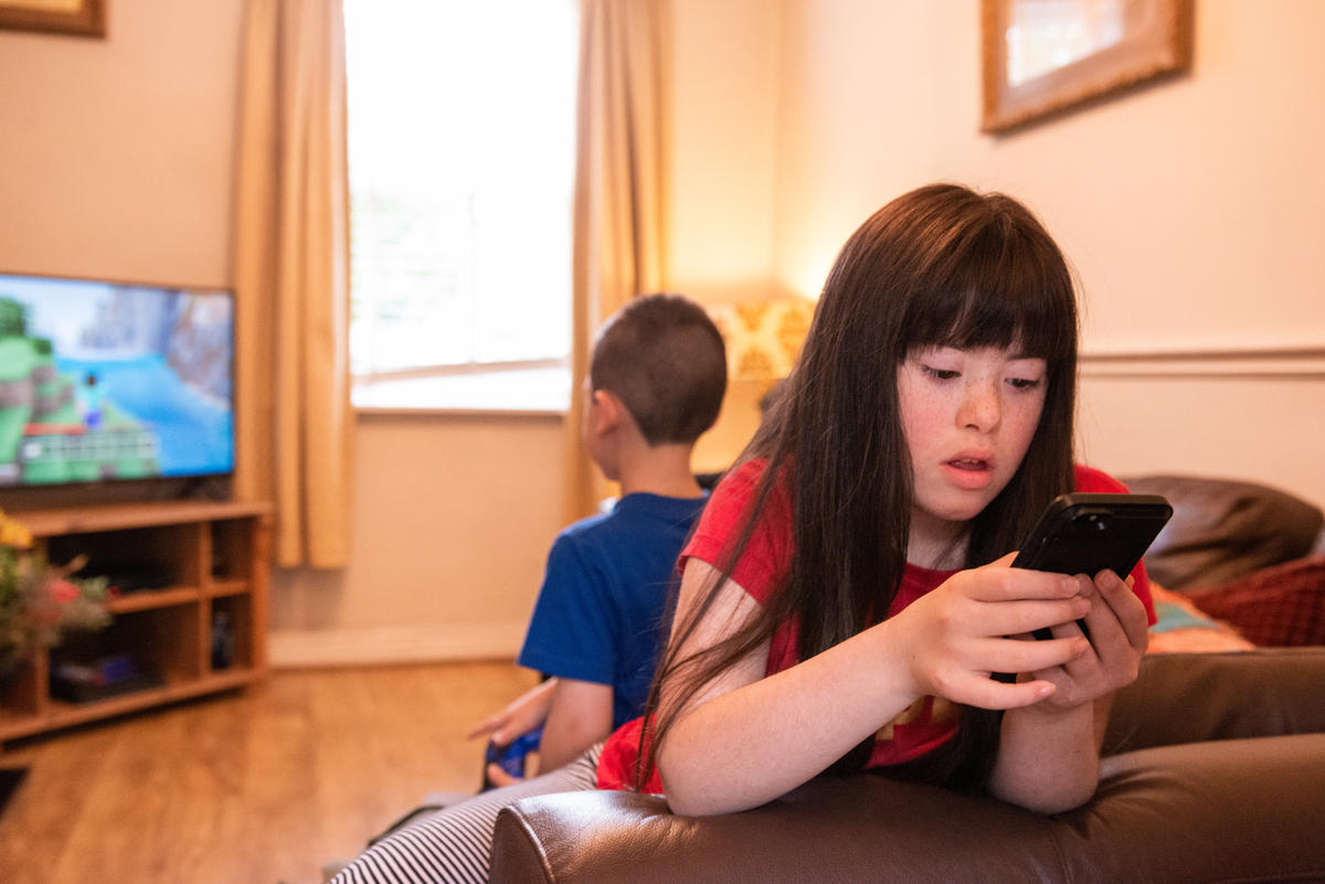 A girl in a red top looking at a mobile phone