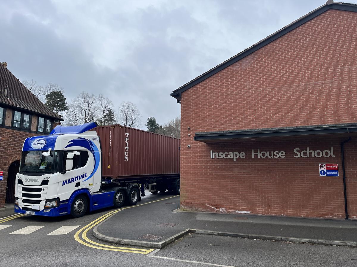 A lorry carrying the huge container next to the front entrance of Inscape House school.