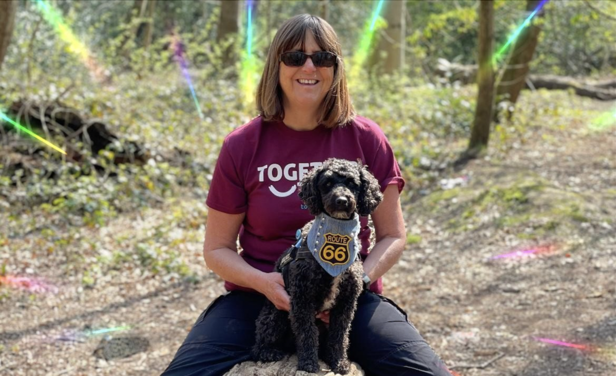 A woman wearing a purple together trust t shirt with a dog sat on her lap