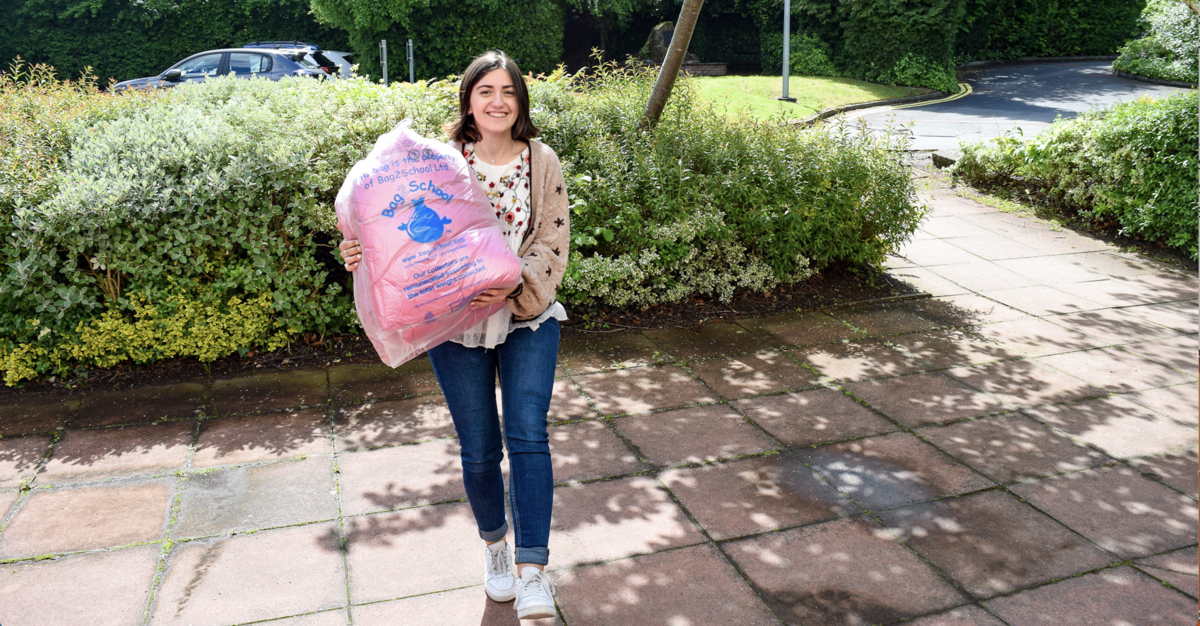 a woman holding a bag of clothes outside