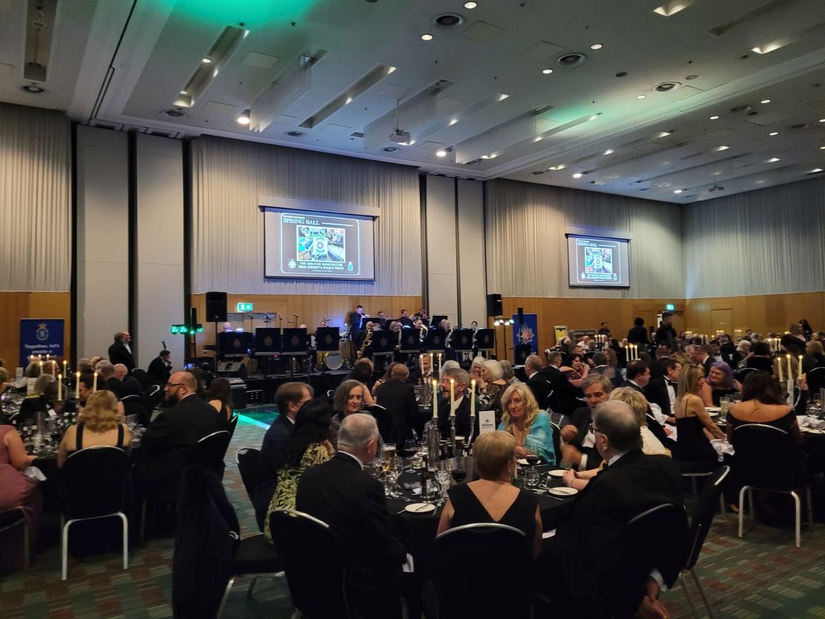 large ballroom full of tables at which people are sitting down enjoying live music. 