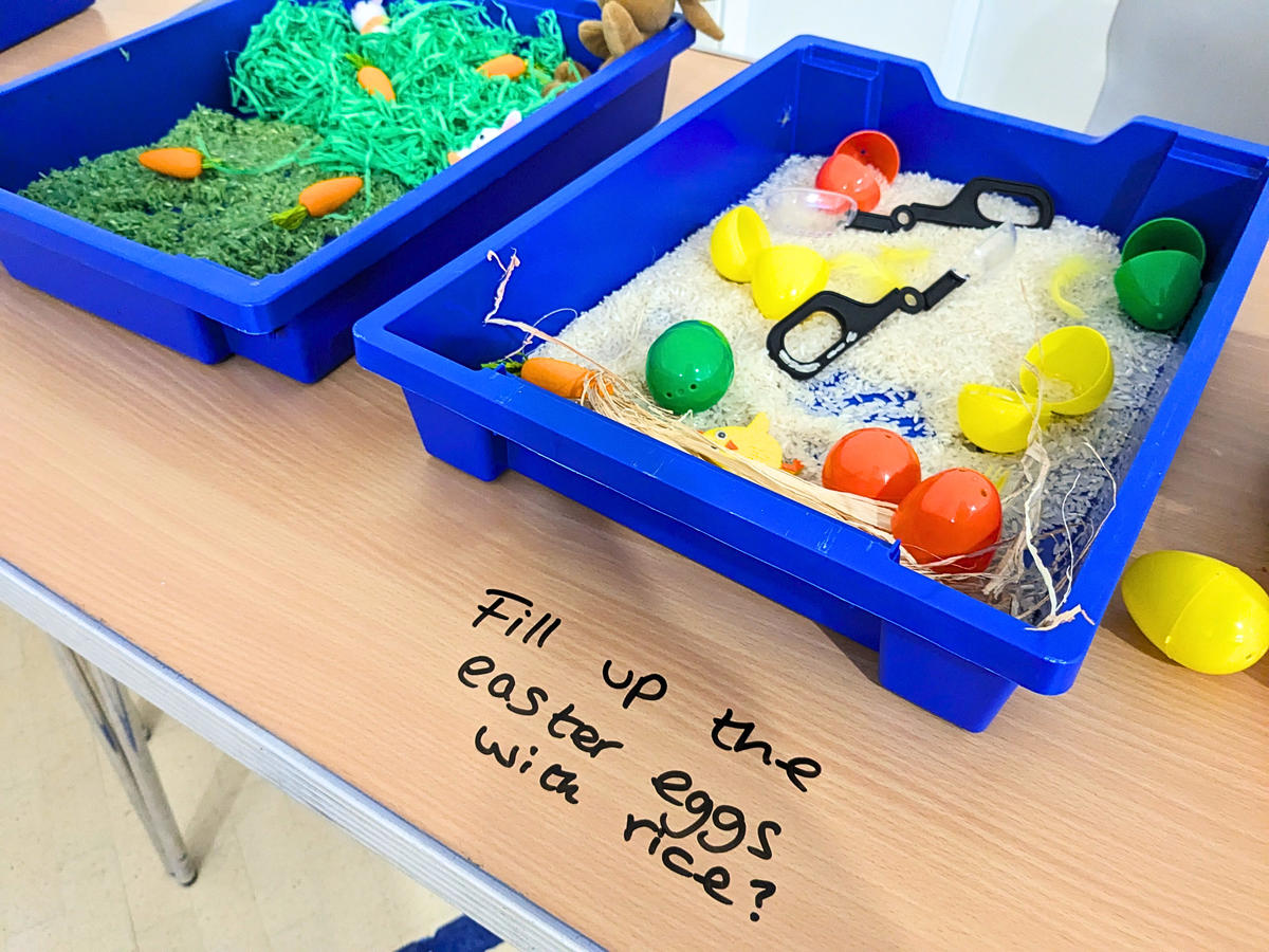 A blue tray filled with rice, plastic egg shells and scoops.