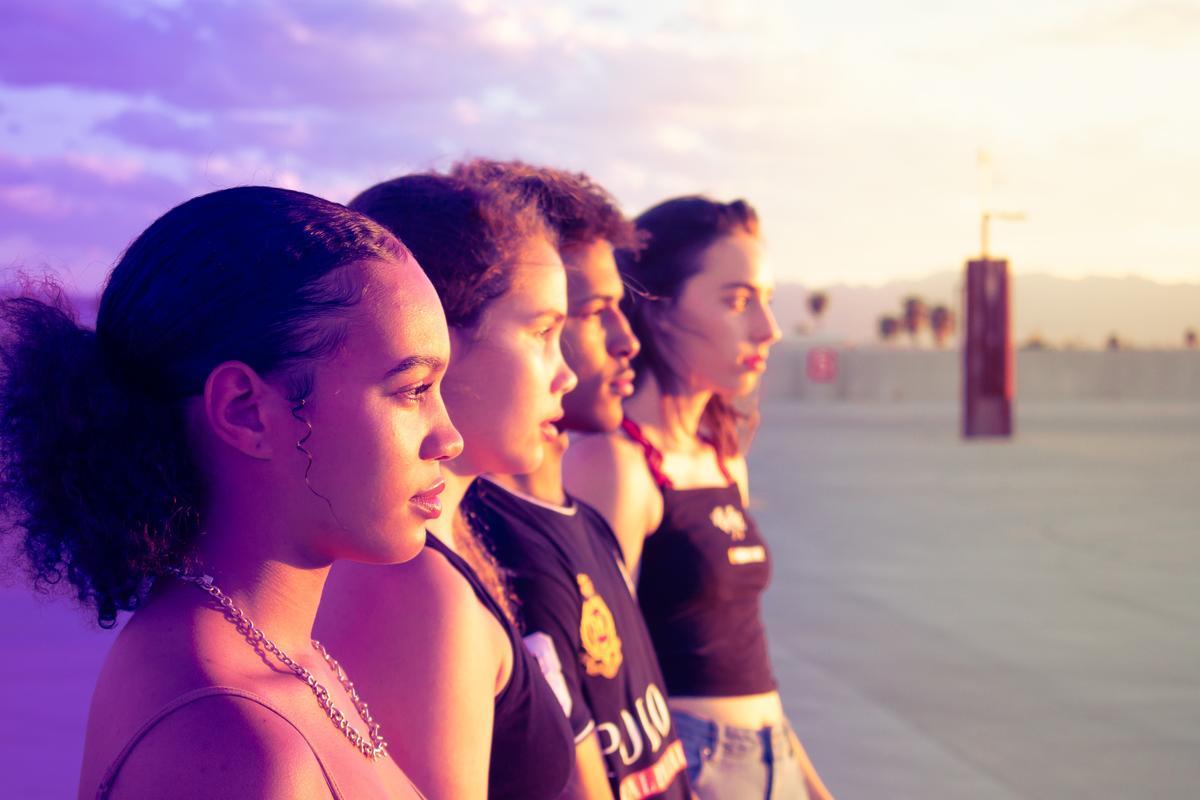 A photo of four teens stood in a row, looking out into the distance.