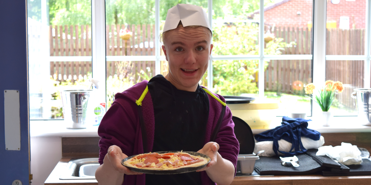 A student smiling while showing the pizza his pizza. A student smiling while showing the pizza his pizza.