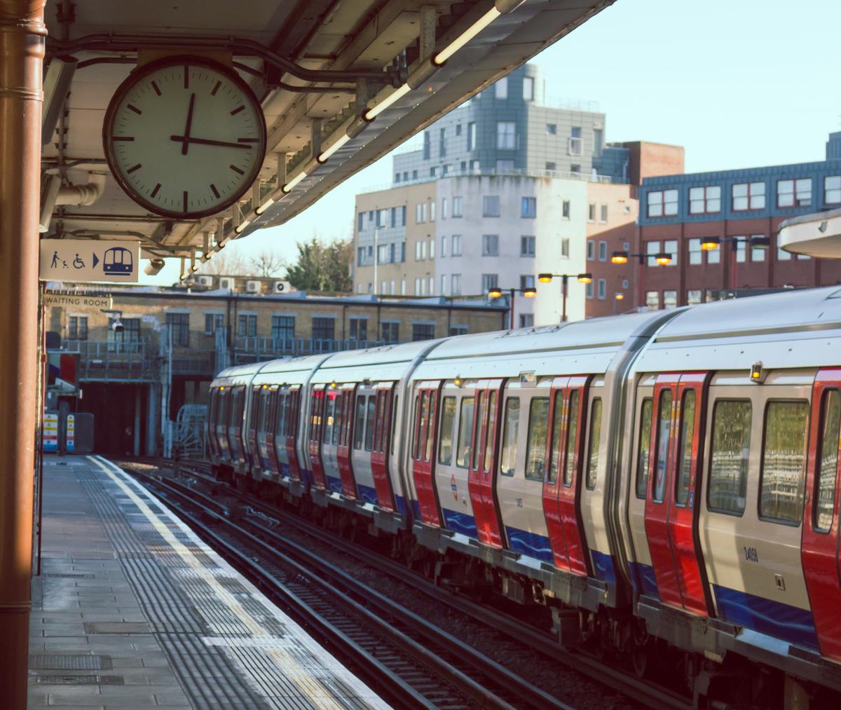 Train station platform on a sunny day. There is a train boarding on the next platform.