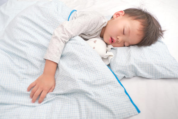 A boy sleeping with a teddy in bed