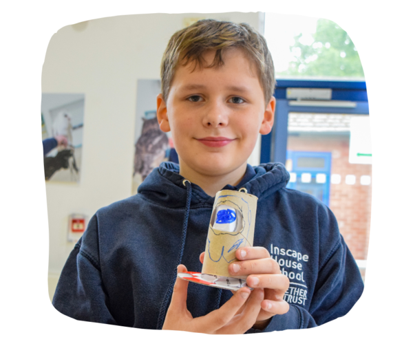 A young boy holding up his empathy doll - a cardboard tube with faces painted on it