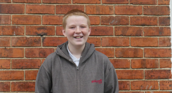 Kyran smiling in front of a brick wall Kyran smiling in front of a brick wall