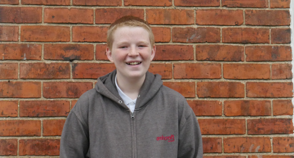 Kyran smiling in front of a brick wall