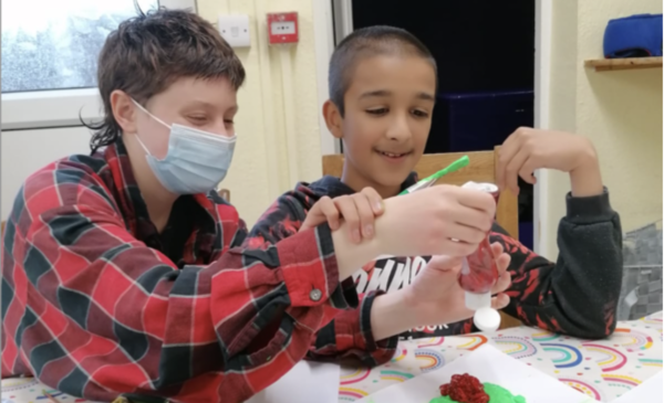A volunteer wearing a face mask helping a resident of one of our homes with some art A volunteer wearing a face mask helping a resident of one of our homes with some art