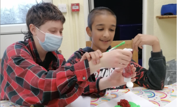 A volunteer wearing a face mask helping a resident of one of our homes with some art