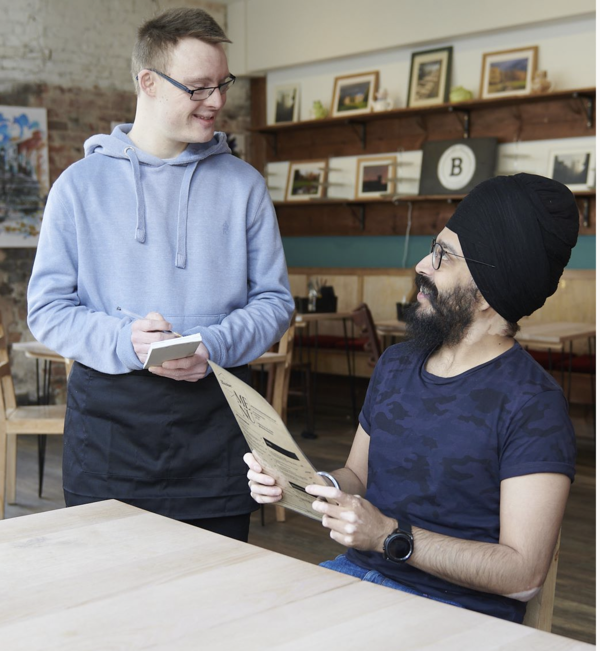 two people in a cafe with one taking the other person's order