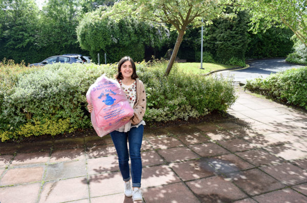 a woman holding a bag full of clothes outside in the sun