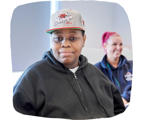 Student wearing a hoodie and cap smiling 