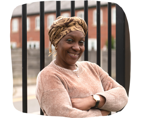 Woman wearing headscarf and jumper crossing her arms smiling at the camera