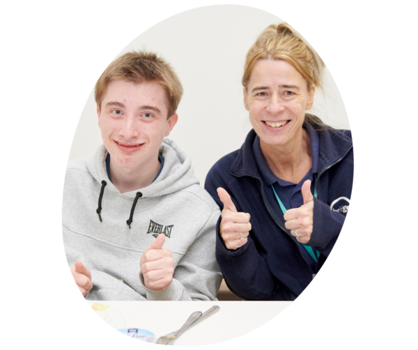 Student and teacher giving the thumbs up while smiling