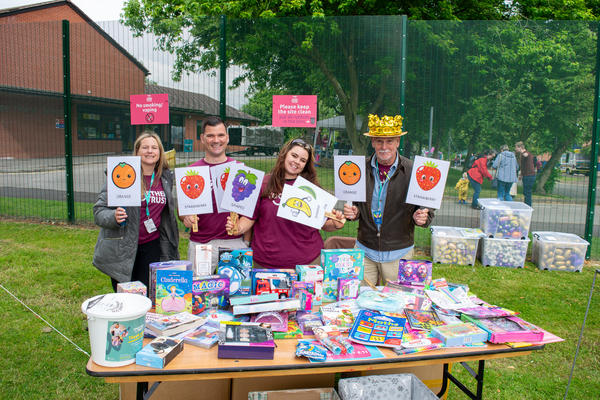 a human tombolla stall with people holding up cards with different fruits on them