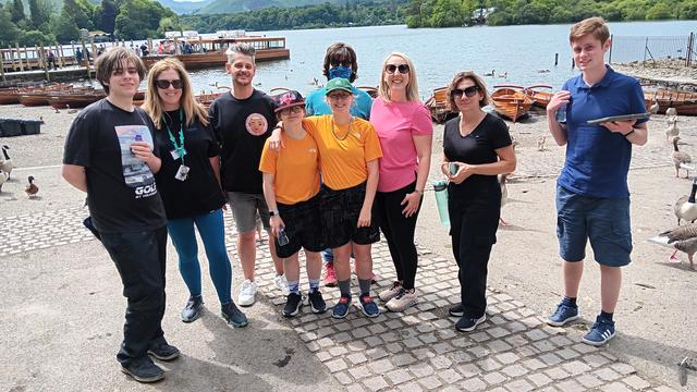 A group of students and staff members posing in front of a lake